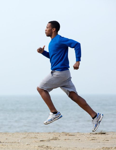 Healthy young athletic man running at the beach